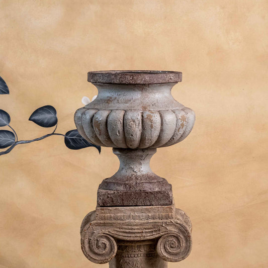 Decorative urn with floral arch on a beige wall