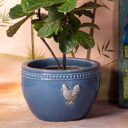 Decorative shelf with decorative items, plant, and stool against a wall with bird design.
