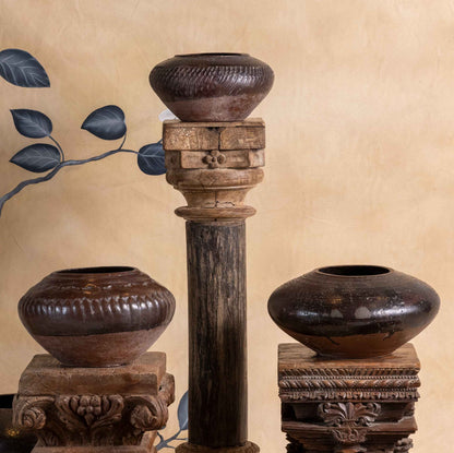 Set of wooden vases and candle holders against a decorative wall with floral patterns.