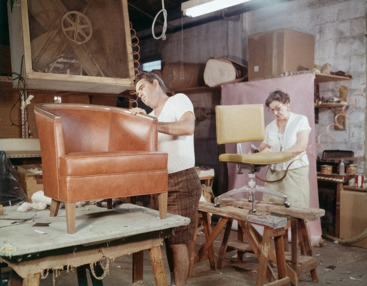 An upholsterer working on a chair in the workshop