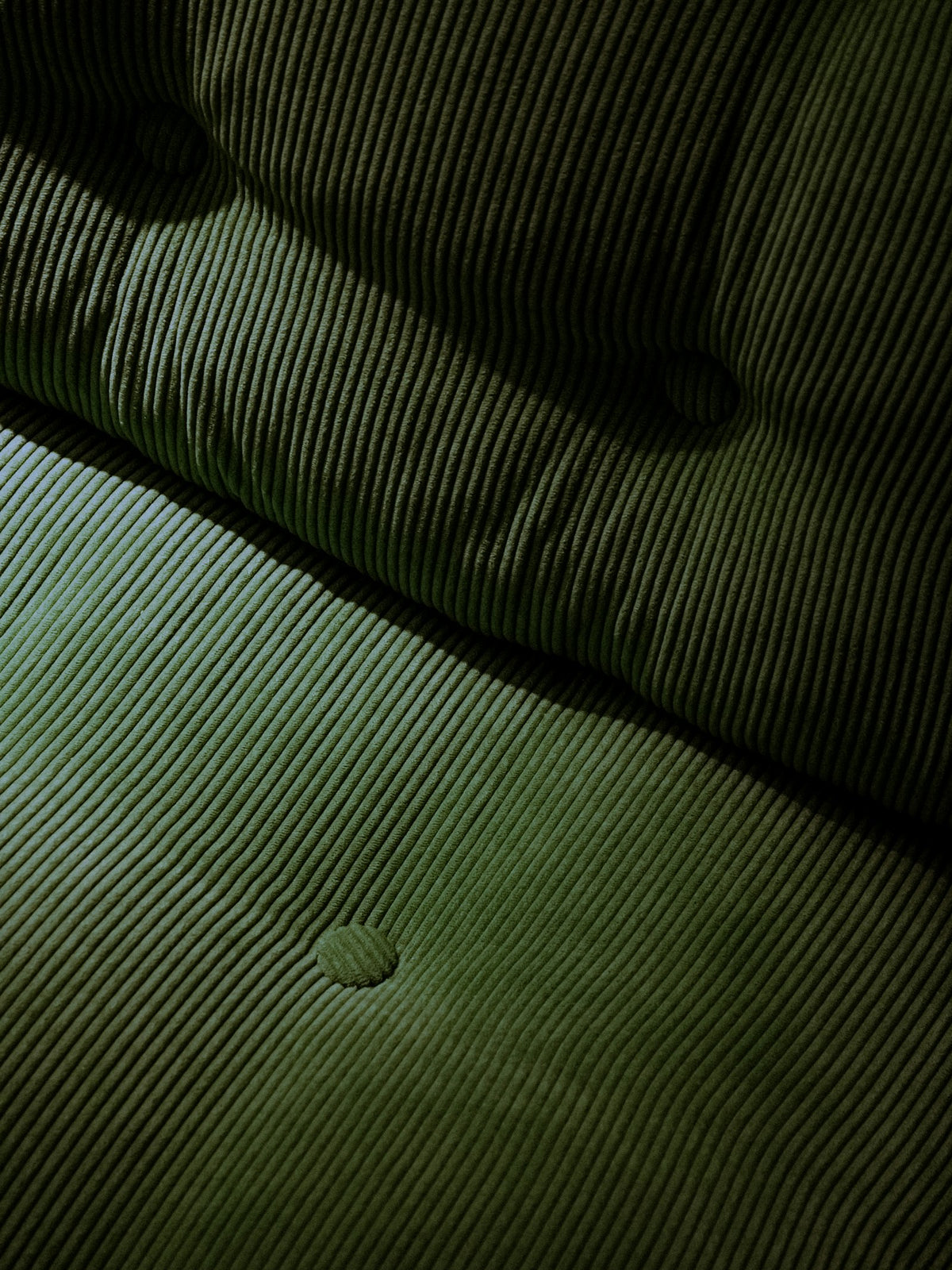 Button tufting pulled into deep green cloth